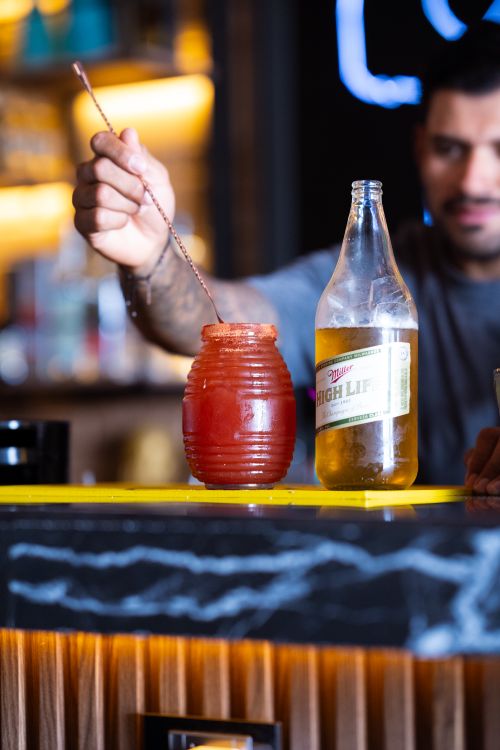 Free A bartender skillfully mixes a refreshing michelada cocktail at a bar counter. Stock Photo