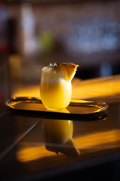 Free A vibrant tropical cocktail with pineapple garnish, captured on an elegant bar counter in warm lighting. Stock Photo