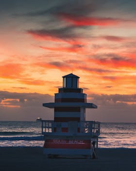 A striking sunrise view of the iconic lifeguard tower on Miami Beach with vivid colors in the sky.
