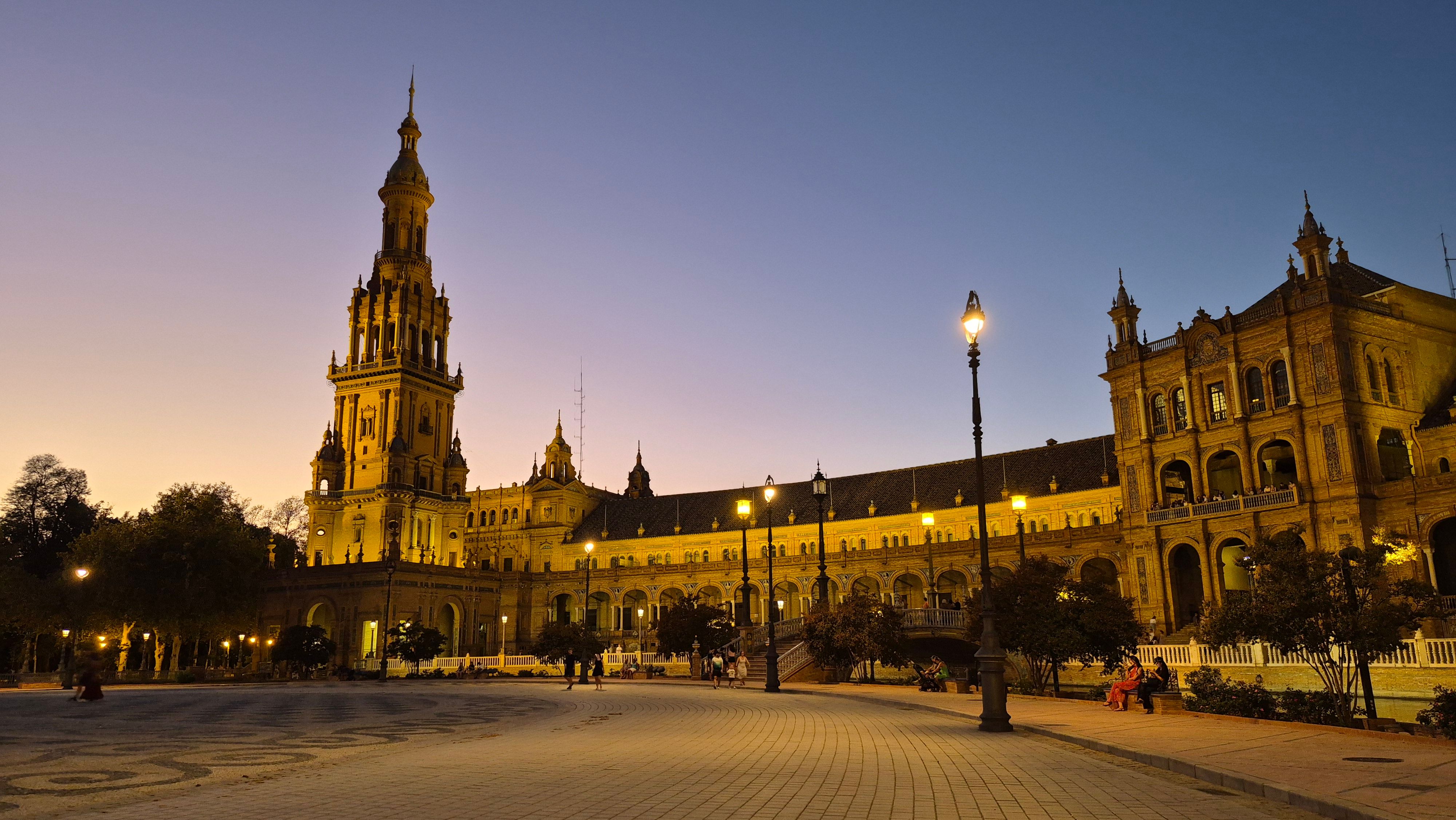 Majestic view of Plaza de España's illuminated architecture during sunset in Seville, Spain.