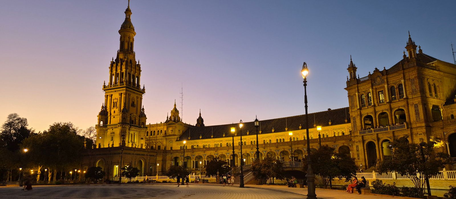 Majestic view of Plaza de España's illuminated architecture during sunset in Seville, Spain.