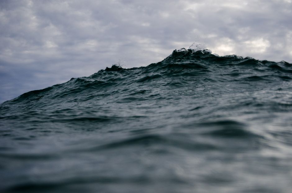 Captivating image of a ocean wave under gloomy, cloudy skies, evoking a sense of nature's power.