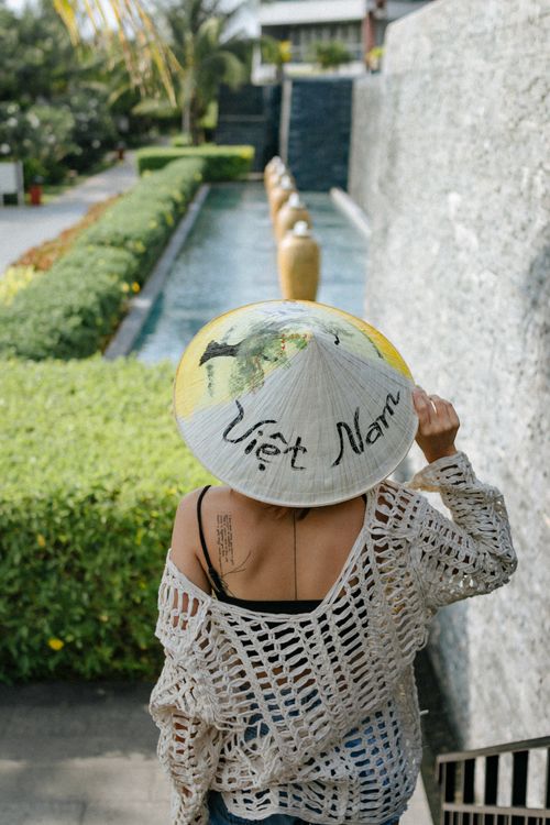Free Back view of a woman wearing a Vietnamese hat walking down a garden path. Stock Photo