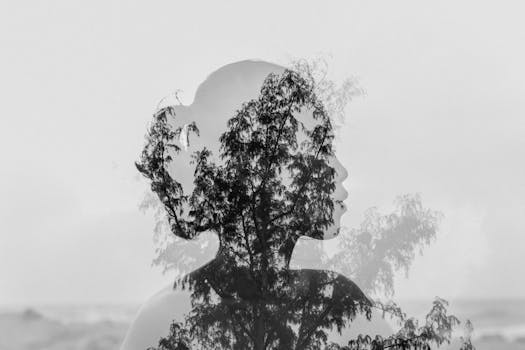 Artistic double exposure capturing a woman's silhouette blending with natural tree branches in black and white.