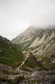Stunning view of cloud-covered mountains in High Tatras with a rocky path. Perfect for nature and travel enthusiasts.