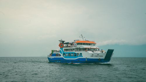Free A vibrant passenger ferry sails smoothly across the calm ocean under a cloudy sky. Stock Photo