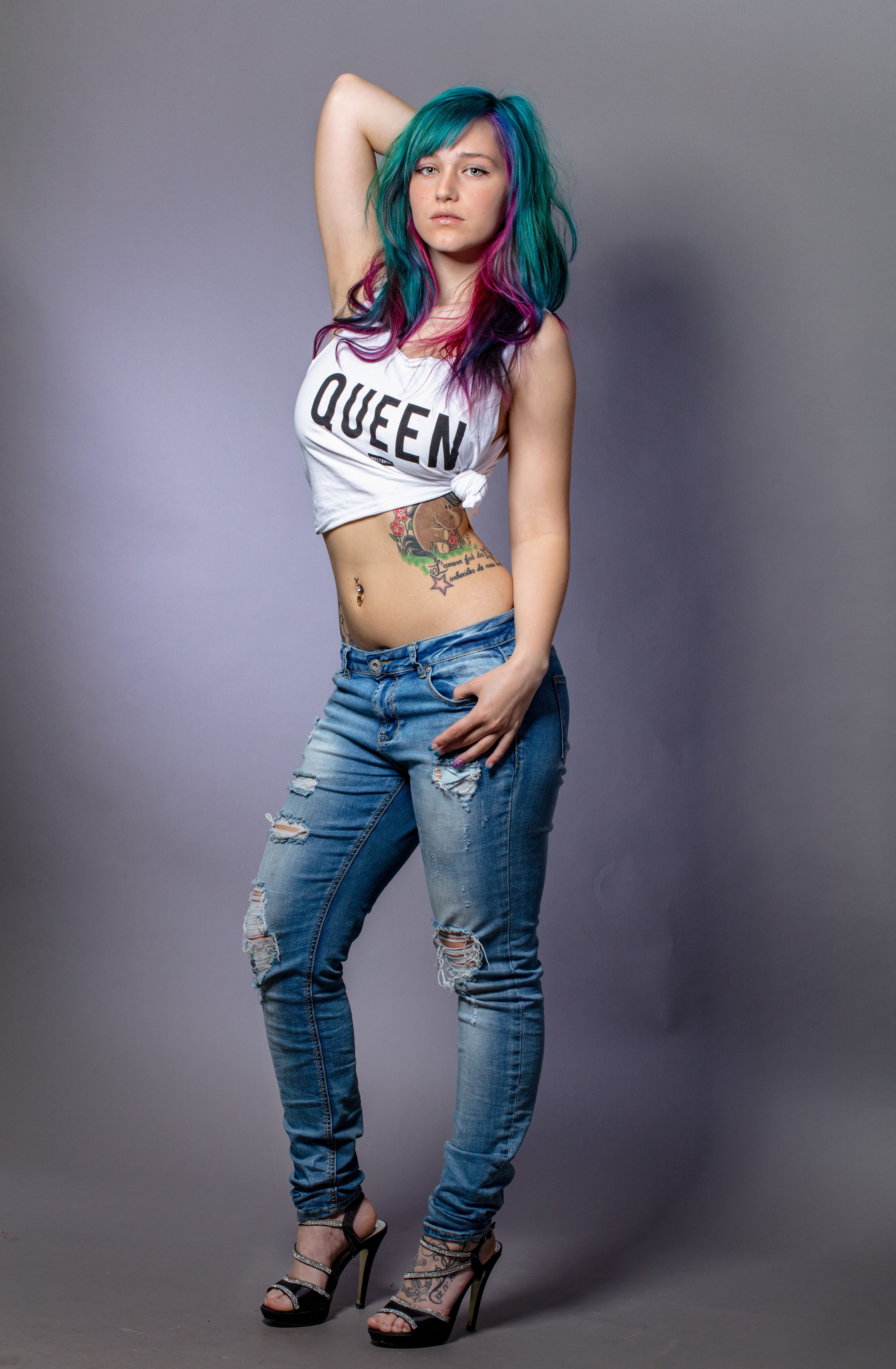 Trendy young woman posing confidently in a crop top and ripped jeans