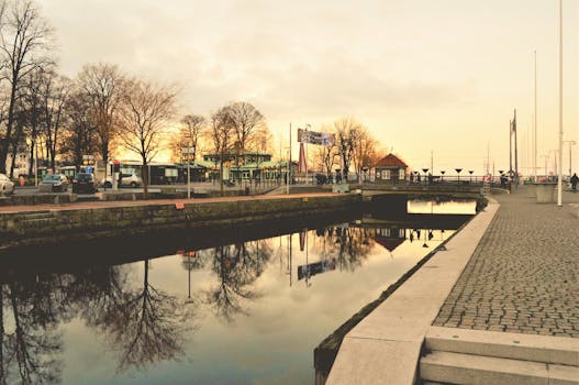 日落时分，运河倒映着树木和建筑，构成宁静的城市景观