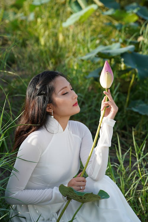 Woman in White Long Sleeve Dress Holding a Flower