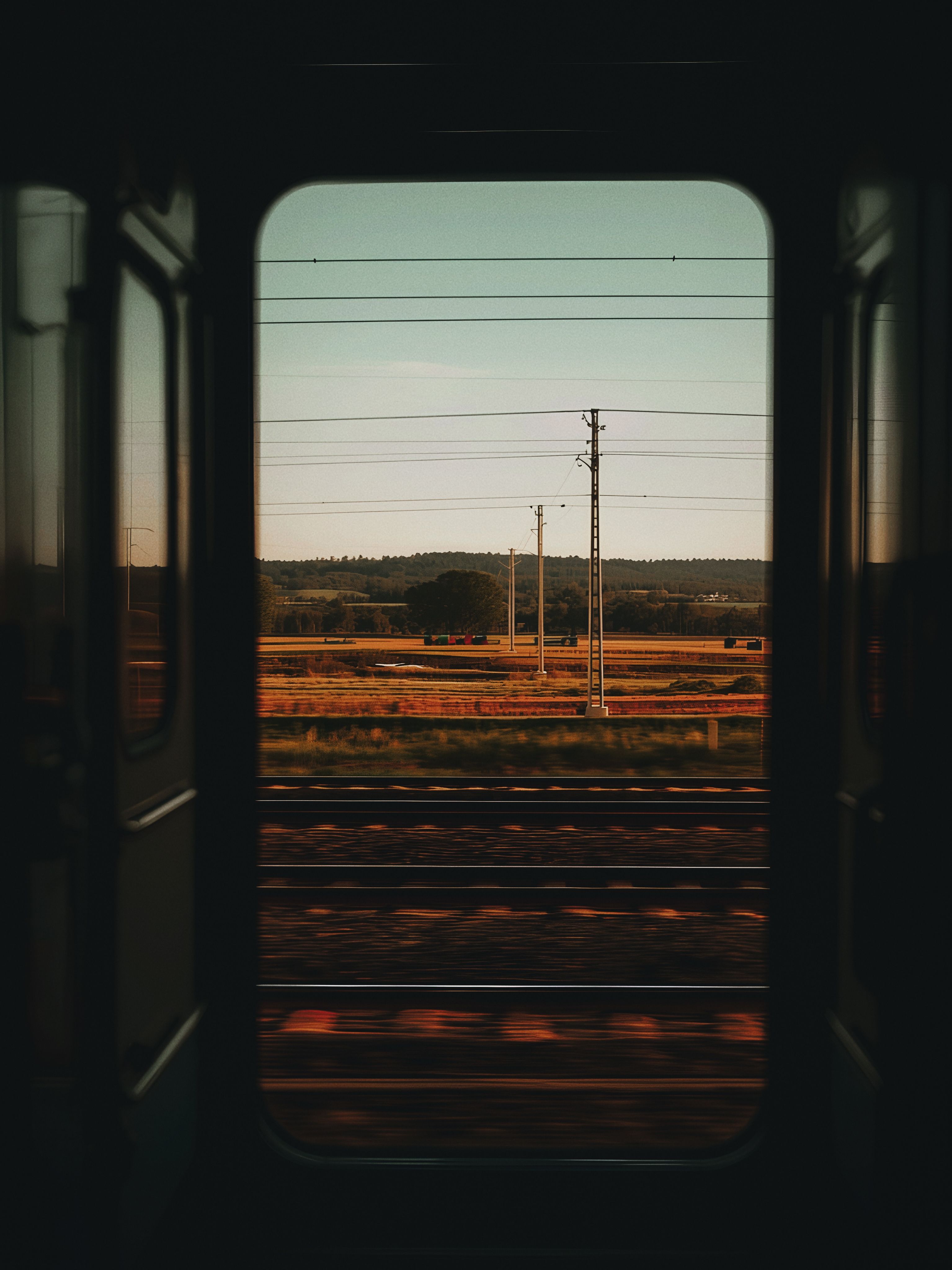 Scenic countryside view from a train window at day with warm tones and minimalistic feel.