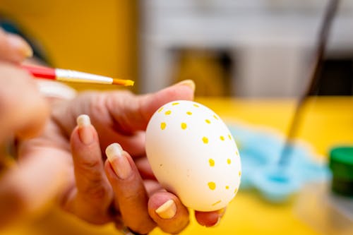 Free  Person Decorating White Egg With Yellow Paint Stock Photo