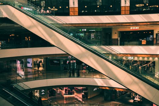 Vibrant shopping mall interior featuring escalators and retail shops across multiple levels.