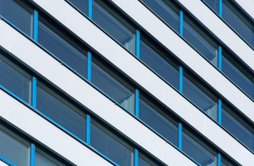 Free Diagonal view of a modern building facade with blue and white geometric design. Stock Photo