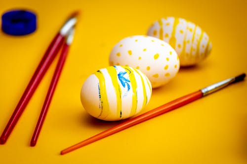 Easter Eggs and Paint Brushes on Yellow Surface