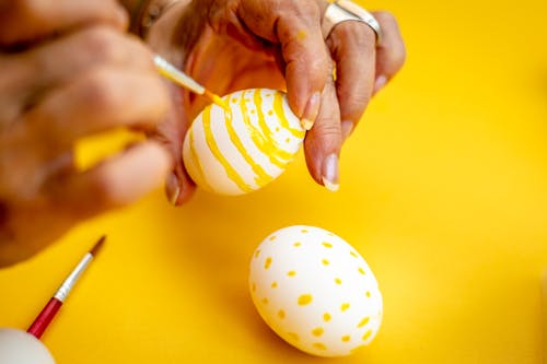 Person Decorating White Egg With Yellow Paint