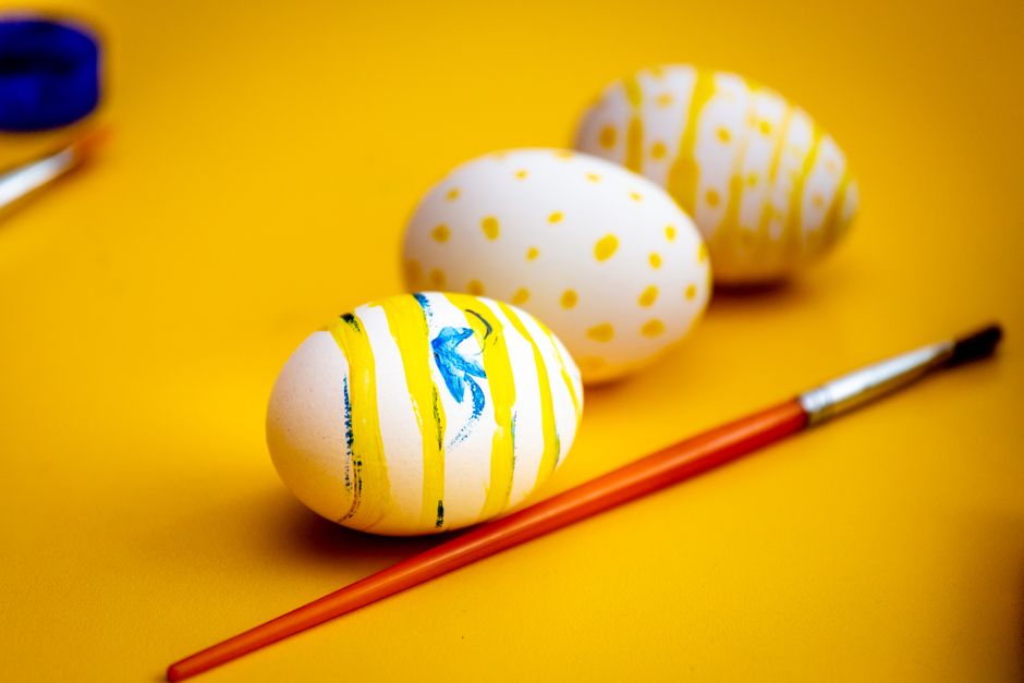 Painted Easter eggs with blue and yellow designs on bright yellow background