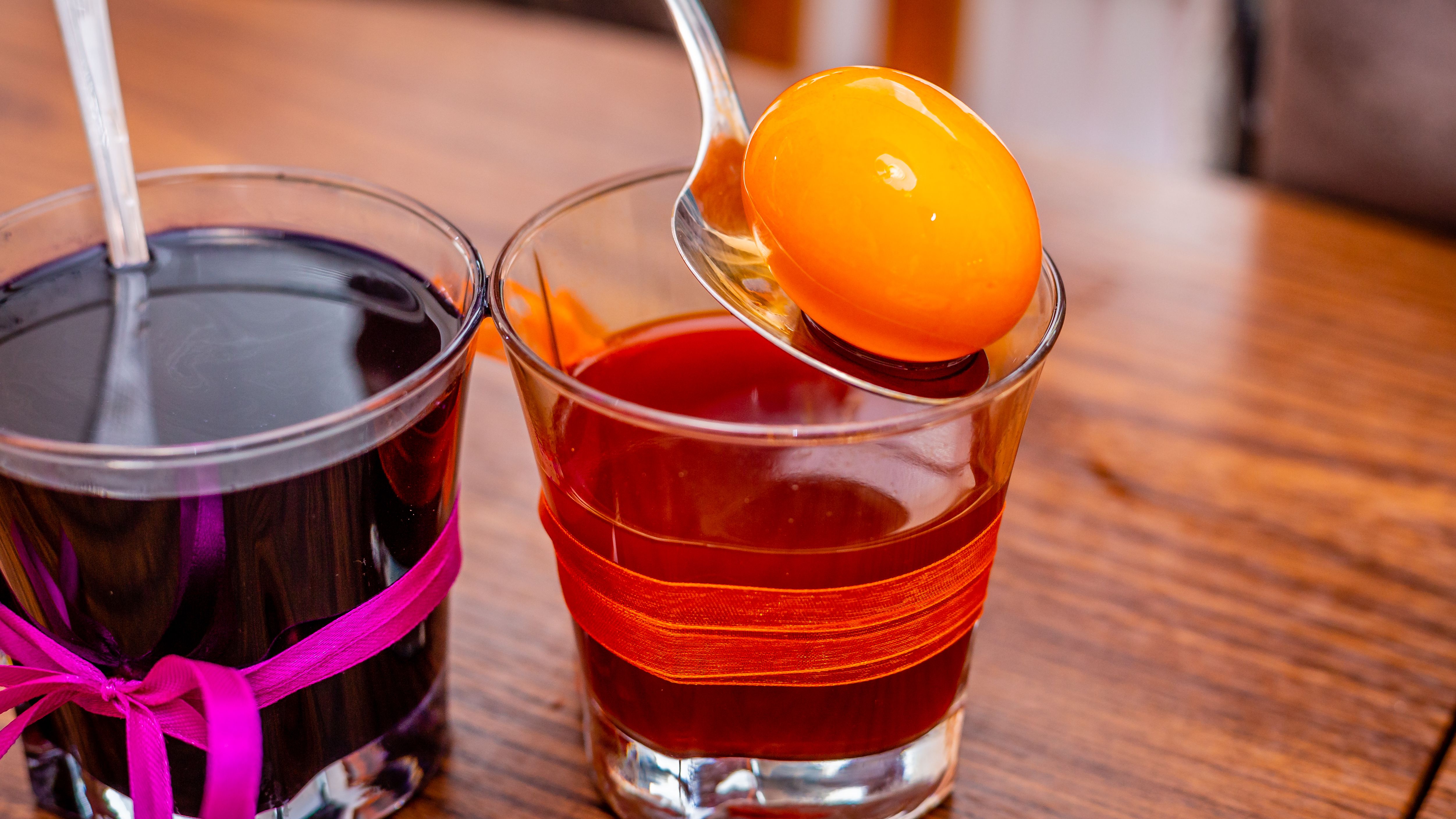 Two Clear Drinking Glasses With Colored Liquids on Wooden Surface
