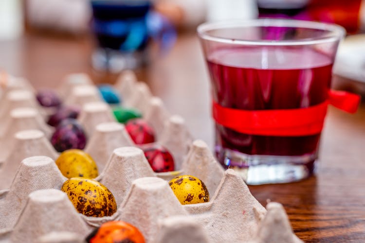 Easter Eggs In Palette Tray Beside Clear Glass With Colored  Liquid