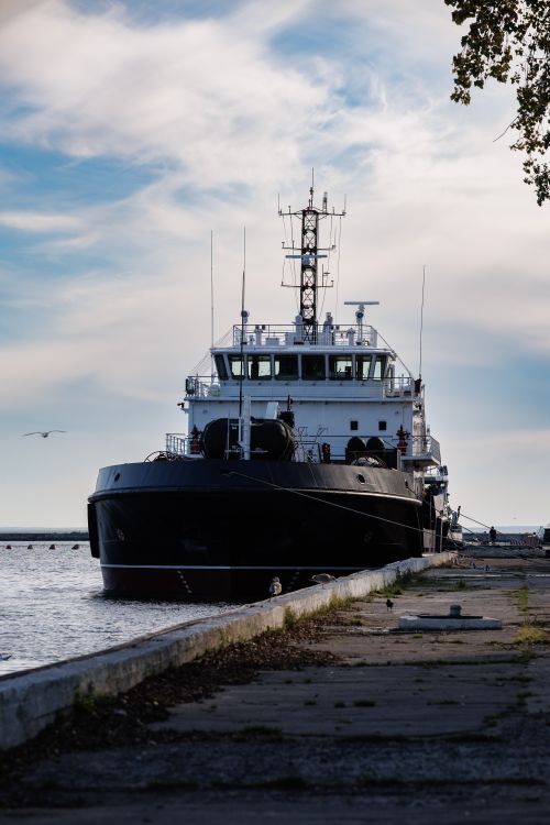Free A formidable black ship moored at Baltiysk harbor against a serene sky. Stock Photo