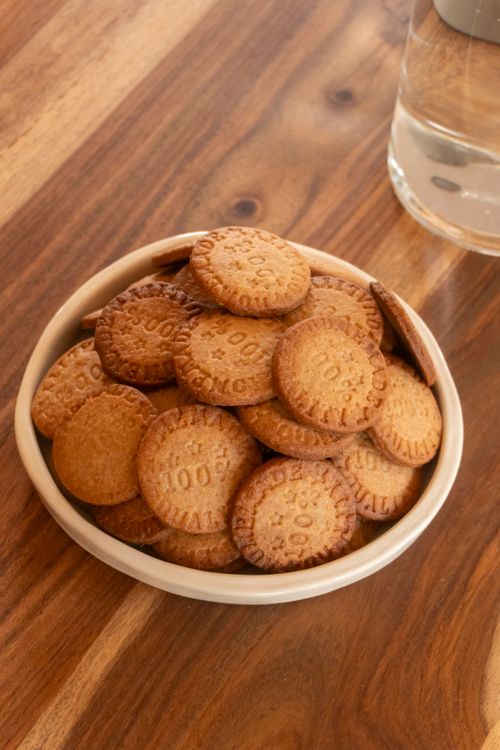 Free A bowl filled with round biscuits on a wooden table, perfect for snack time. Stock Photo