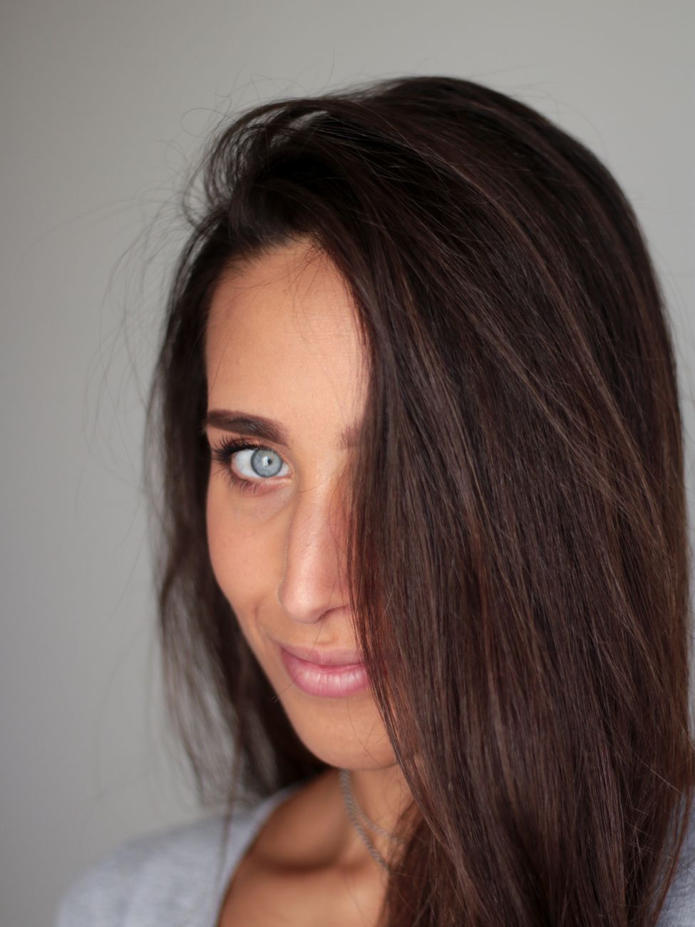 Close-up portrait of a woman with captivating blue eyes and long brunette hair, exuding elegance.