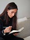 Woman in Black Sweater Holding a Notebook