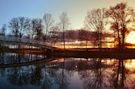 在瑞典大桥上，美丽的日落映照在平静的湖面上，树木倒映其中