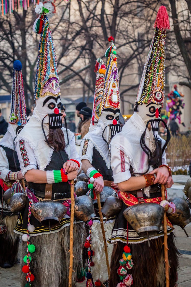 People Wearing Costumes And Masks Holding Sticks