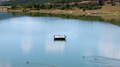 Free Peaceful lake view with birds perched on a platform and serene surroundings. Stock Photo