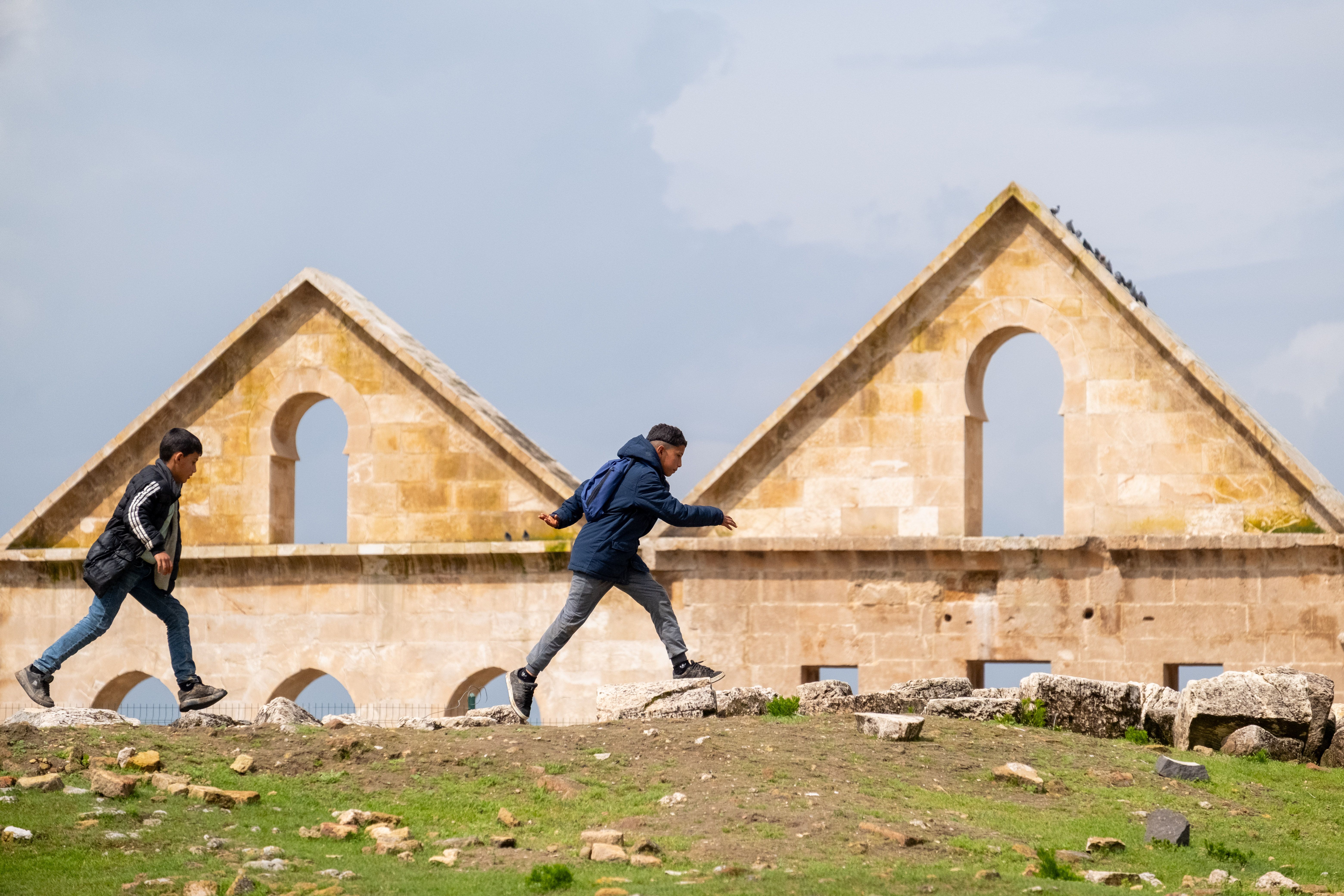 Two boys explore ancient stone ruins under a bright blue sky, capturing the spirit of adventure - school district licensing