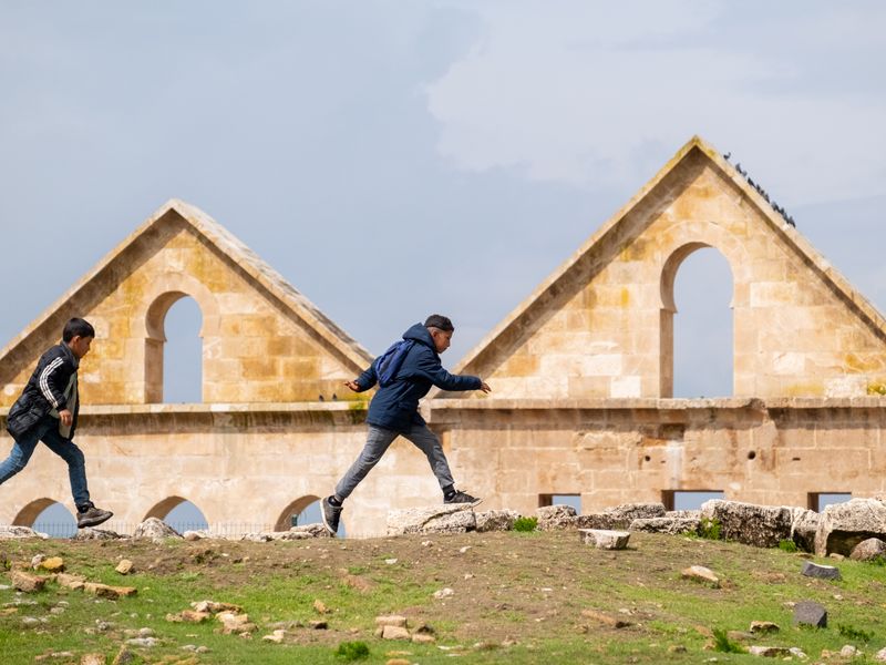 Two boys explore ancient stone ruins under a bright blue sky, capturing the spirit of adventure - school district licensing