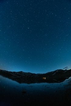 A breathtaking view of a starry night sky reflecting on a serene mountain lake.