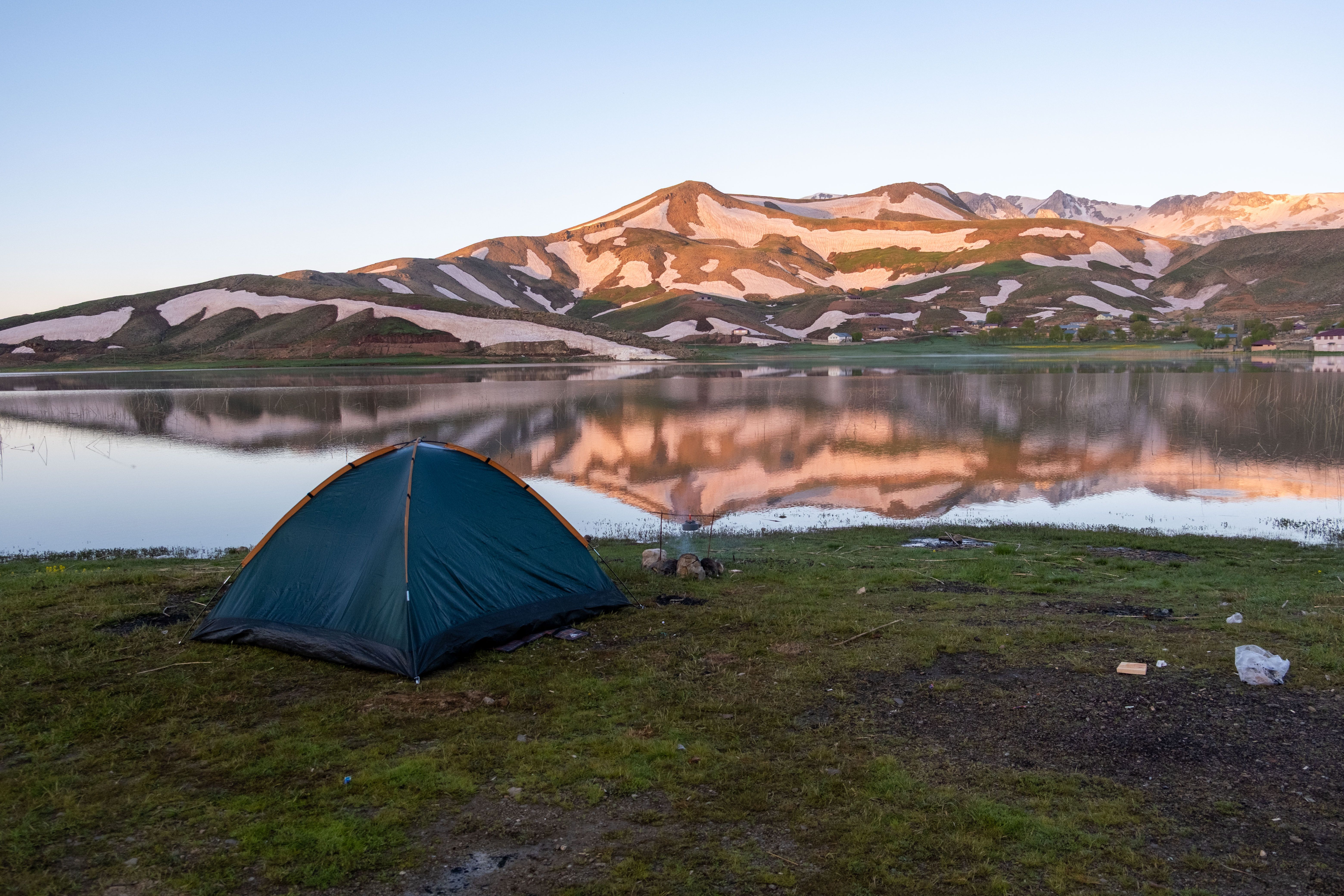 Petite tente installée au bord d'un lac de montagne au lever du jour