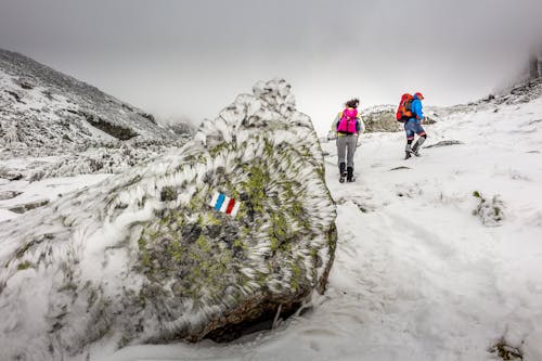 People Hiking On Mountain Covered With Snow