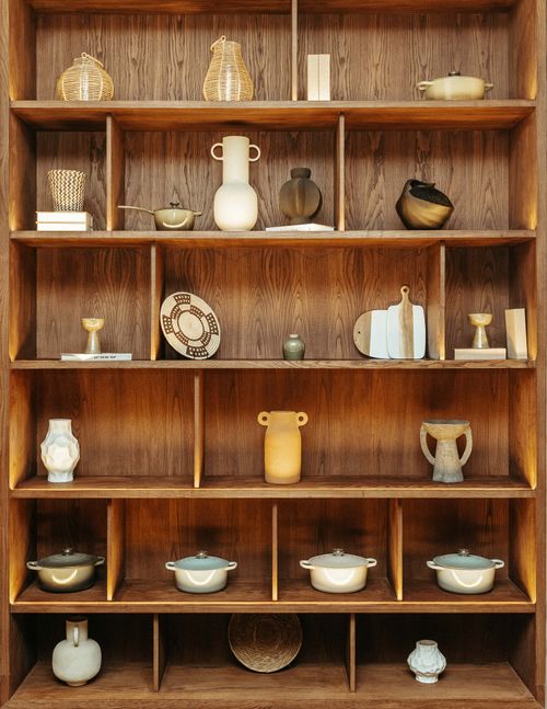 Free A wooden shelf beautifully arranged with various ceramic and pottery pieces in a cozy indoor setting. Stock Photo