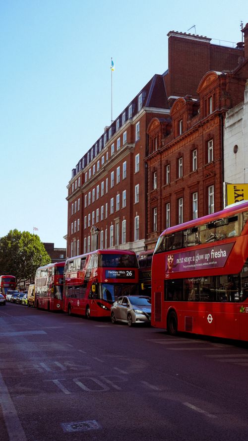 Free Iconic red double-decker buses on a street in London, UK, with classic brick architecture. Stock Photo
