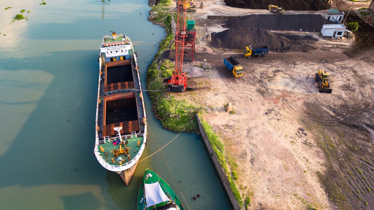 Aerial view of a cargo ship berthed with trucks at a river port in Dhaka