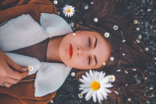 一位年轻女子躺在雏菊地里，周围鲜花环绕