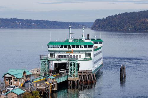 Free Washington State ferry docking with vehicles onboard in serene coastal landscape. Stock Photo