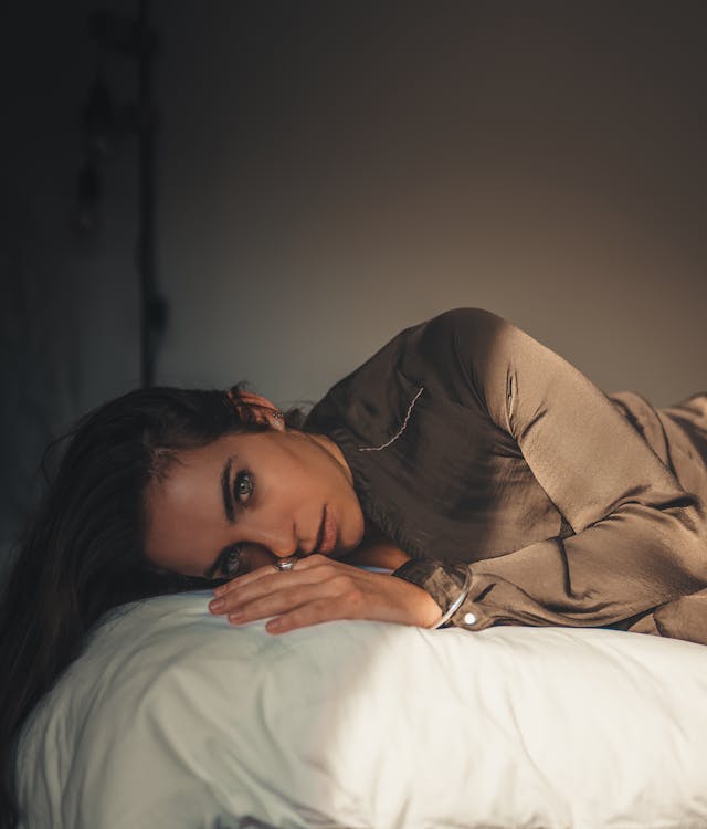 Free Woman in Brown Long Sleeve Shirt Lying on Bed Stock Photo