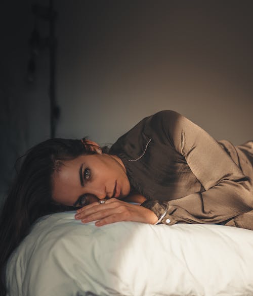 Woman in Brown Long Sleeve Shirt Lying on Bed