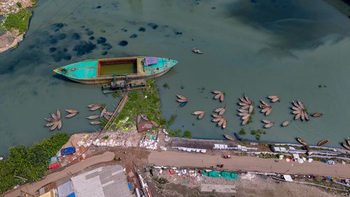 Free A captivating aerial view of boats and a cargo ship docked by a riverbank, surrounded by lush greenery. Stock Photo