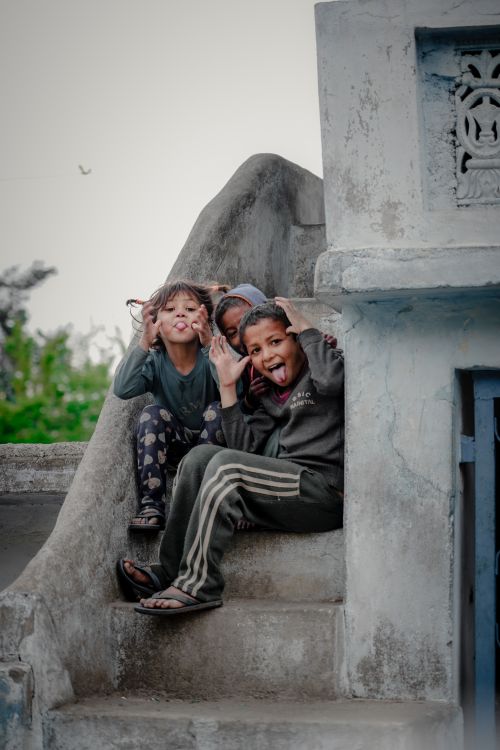 Free Three children playfully posing on an urban staircase, enjoying the moment. Stock Photo
