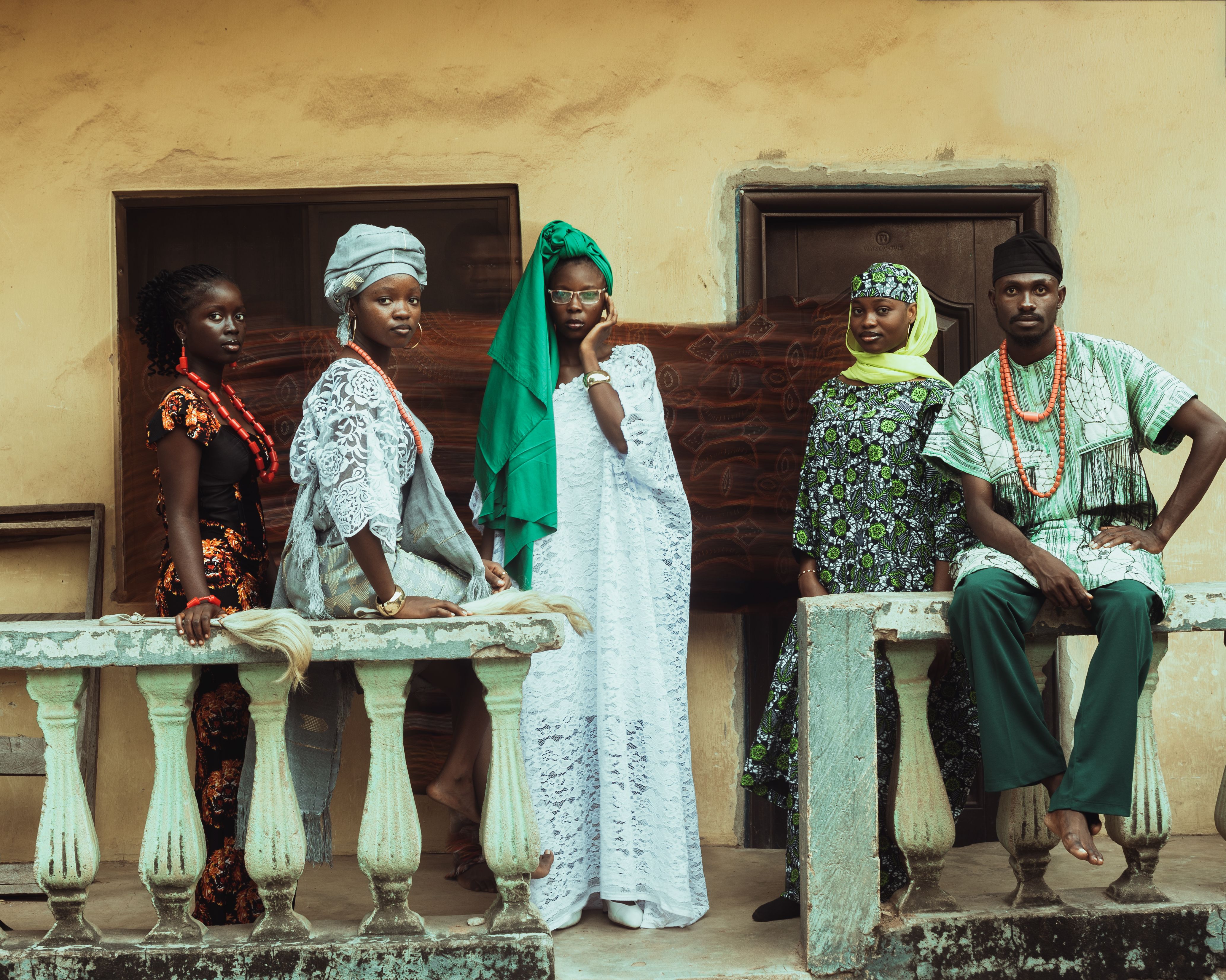 Five adults in traditional attire pose on an ornate balcony, showcasing cultural diversity.