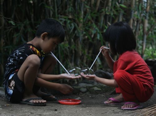 Free Two children playing with bubble wands outdoors in Yogyakarta, Indonesia. Stock Photo