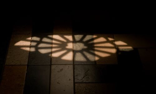 Free Moody shadow of rose window casting on a tiled floor. Stock Photo