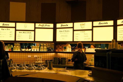 Free Warm, inviting gelato shop interior in Glebe, New South Wales, showing illuminated menu and patrons. Stock Photo