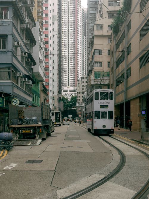 Free Hong Kong street scene featuring an iconic tram amidst tall buildings, capturing urban life. Stock Photo