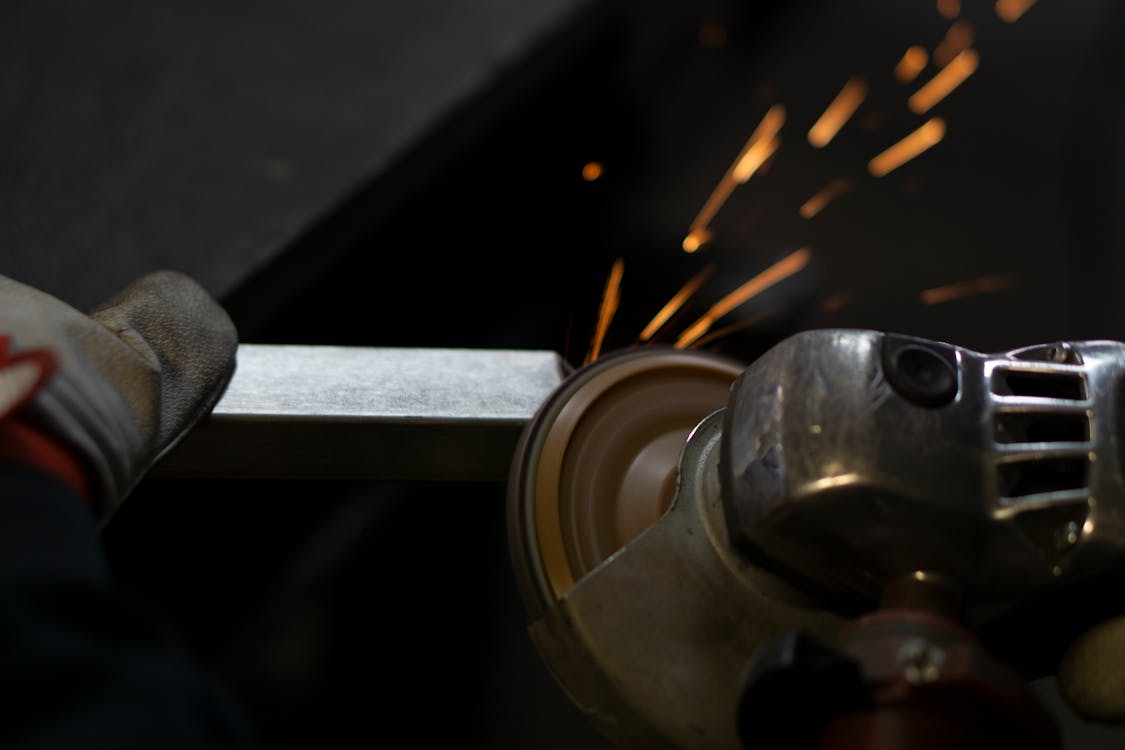 Person Using Angle Grinder on a Piece of Metal
