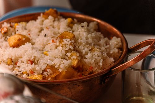 Free Savor the taste of homemade fried rice with crispy golden pieces served in a rustic copper pan. Stock Photo